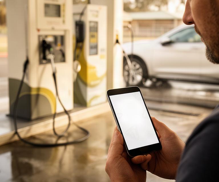 Customer checking a car wash website on a phone beside a self-service wash bay in Benalla